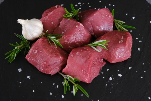 Diced game meat with rosemary on a slate board