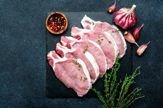 Raw pork chops on a wooden board